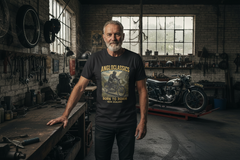 Black t-shirt with a graphic of a person on a motorcycle and text 'Angloclassics Born to Roam New Zealand' on a white background.